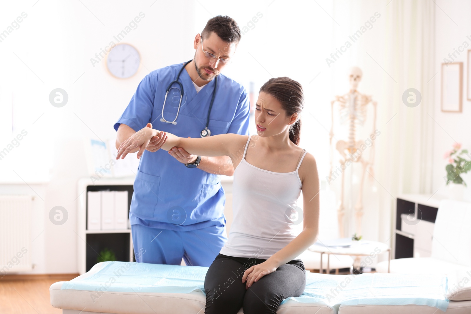 Photo of Male orthopedist examining patient's arm in clinic