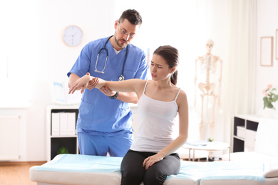 Male orthopedist examining patient's arm in clinic