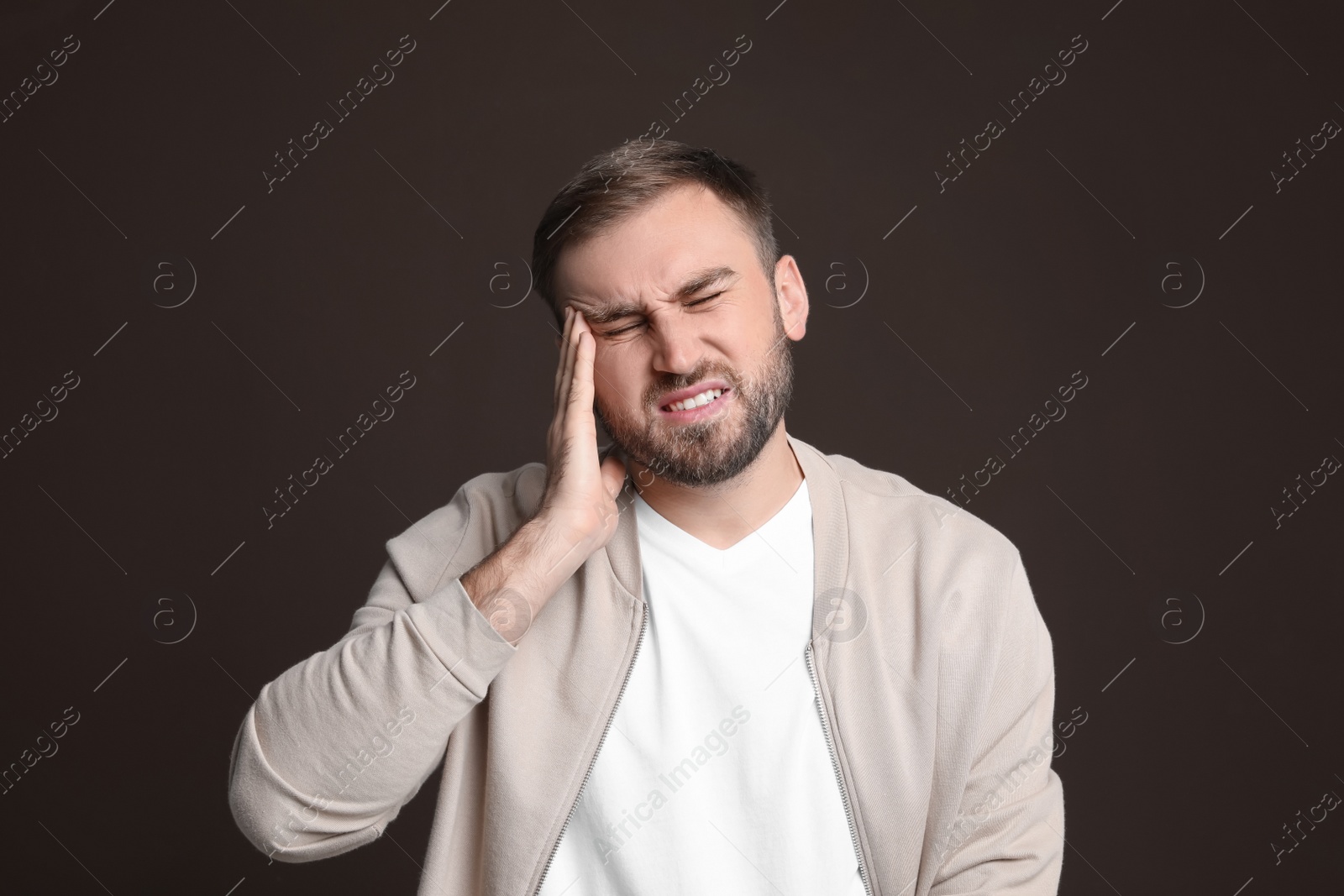 Photo of Young man suffering from headache on dark background