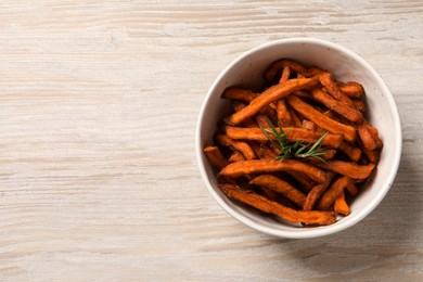 Bowl with sweet potato fries and rosemary on wooden table, top view. Space for text