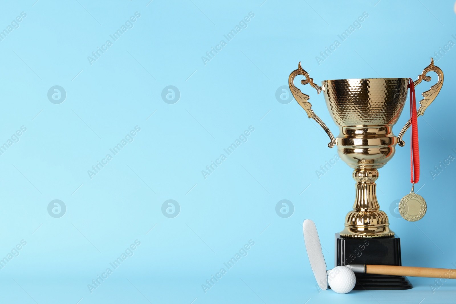 Photo of Golden trophy cup, medal, golf club and ball on color background. Space for text
