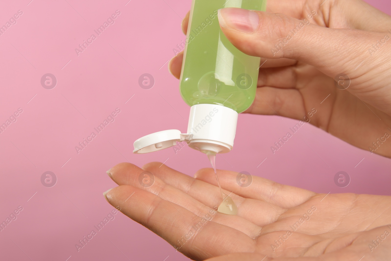 Photo of Woman applying antiseptic gel on pink background, closeup