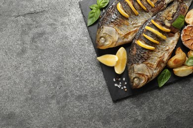 Photo of Tasty homemade roasted crucian carps served on grey table, top view and space for text. River fish