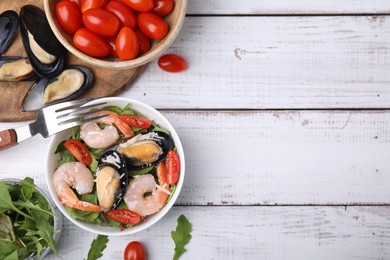 Bowl of delicious salad with seafood on white wooden table, flat lay. Space for text
