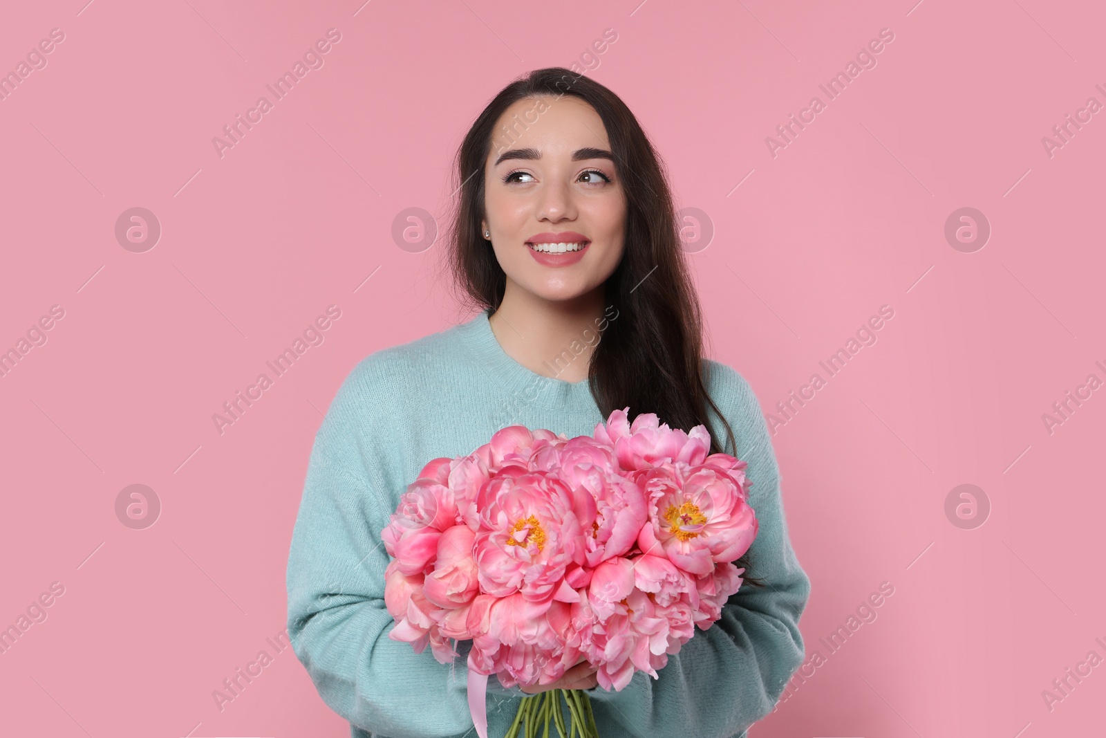 Photo of Beautiful young woman with bouquet of peonies on pink background