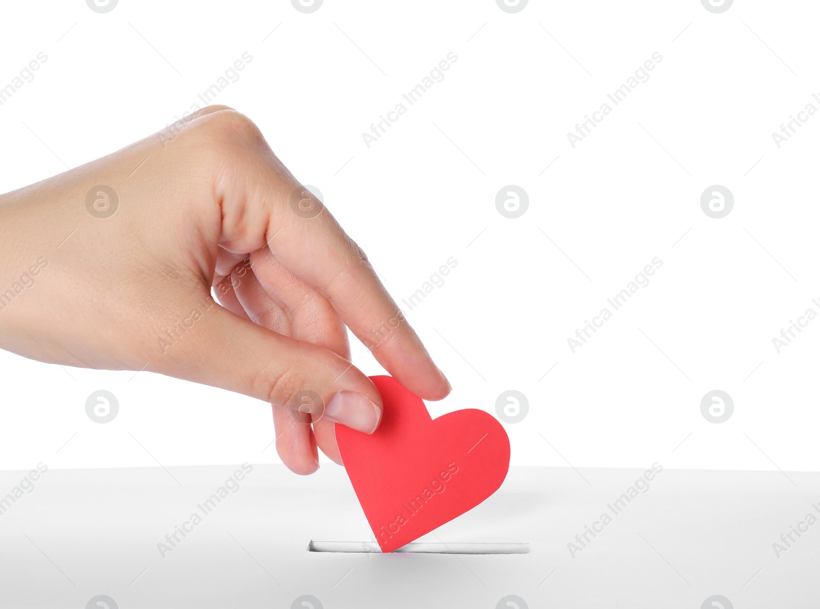 Photo of Woman putting red heart into slot of donation box against white background, closeup