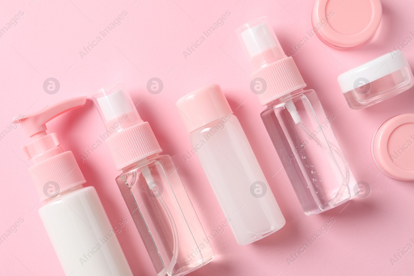 Photo of Cosmetic travel kit on pink background, flat lay. Bath accessories