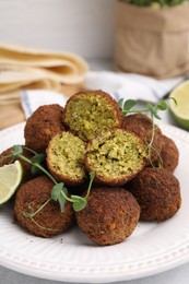 Photo of Delicious falafel balls and microgreens on table