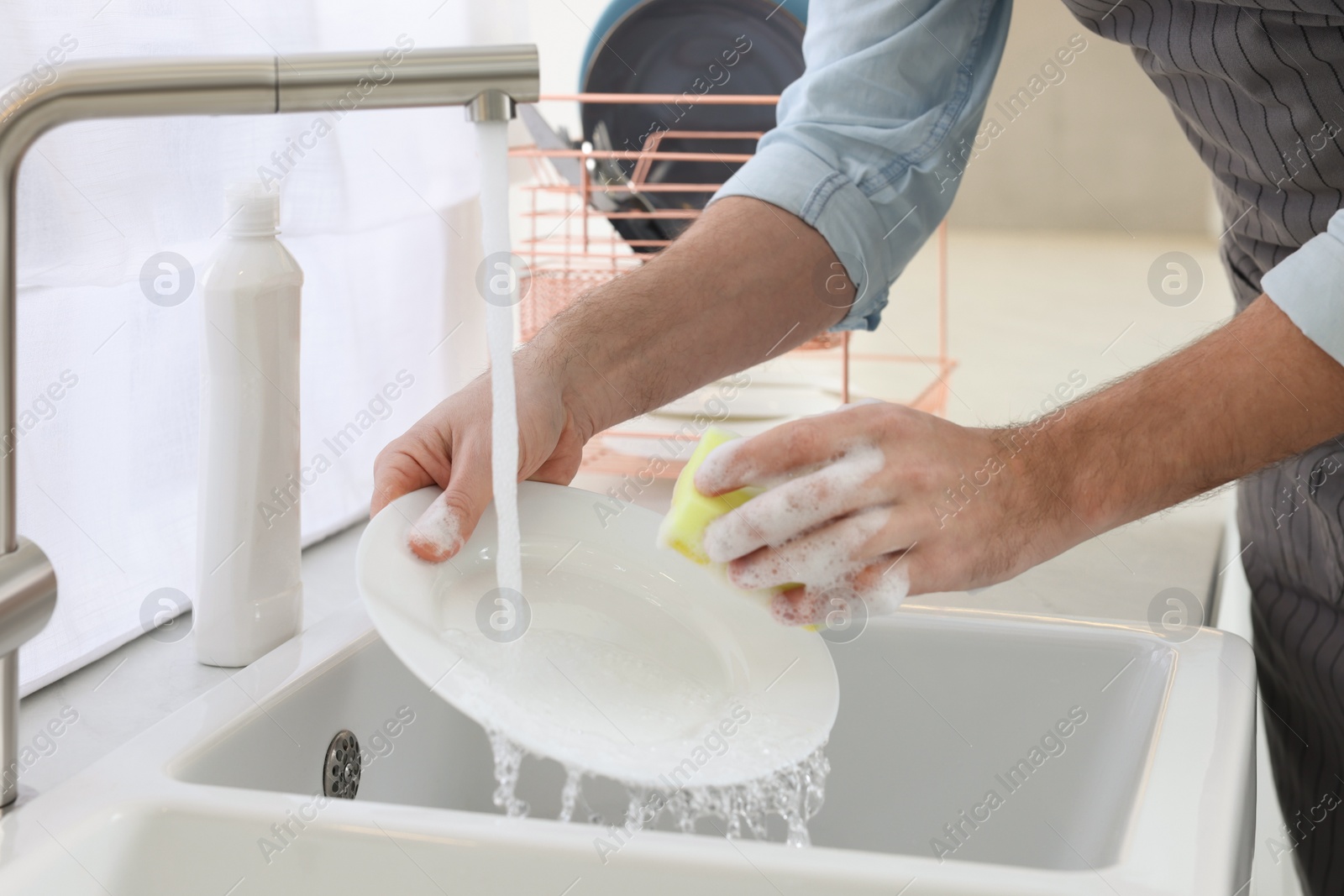 Photo of Man washing plate above sink in kitchen, closeup