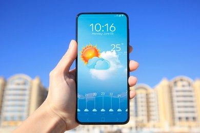 Image of Man using weather forecast app on smartphone outdoors on sunny day, closeup. Data and illustration of sun with cloud on screen