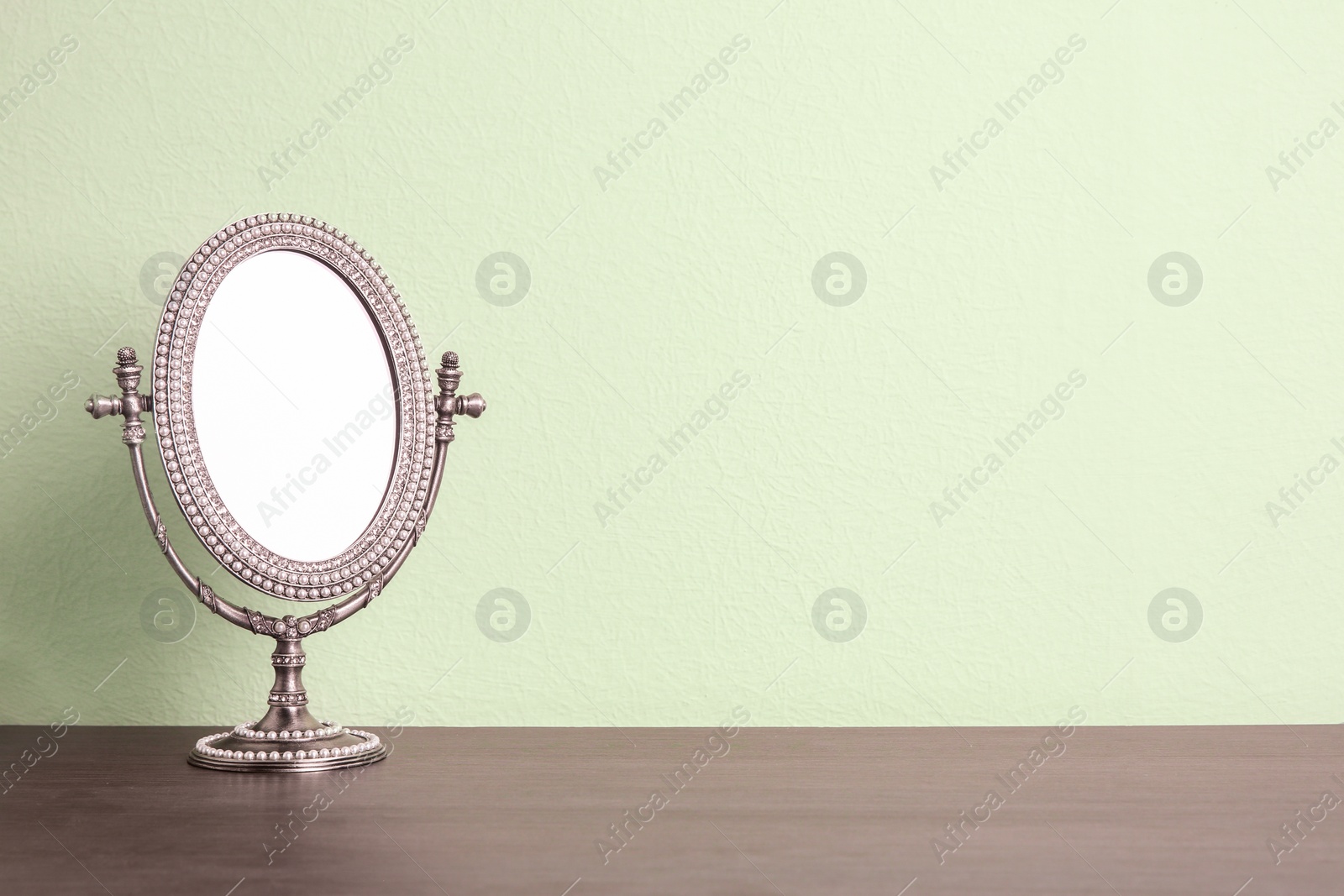 Photo of Stylish mirror on table near light wall