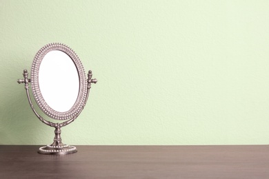 Photo of Stylish mirror on table near light wall