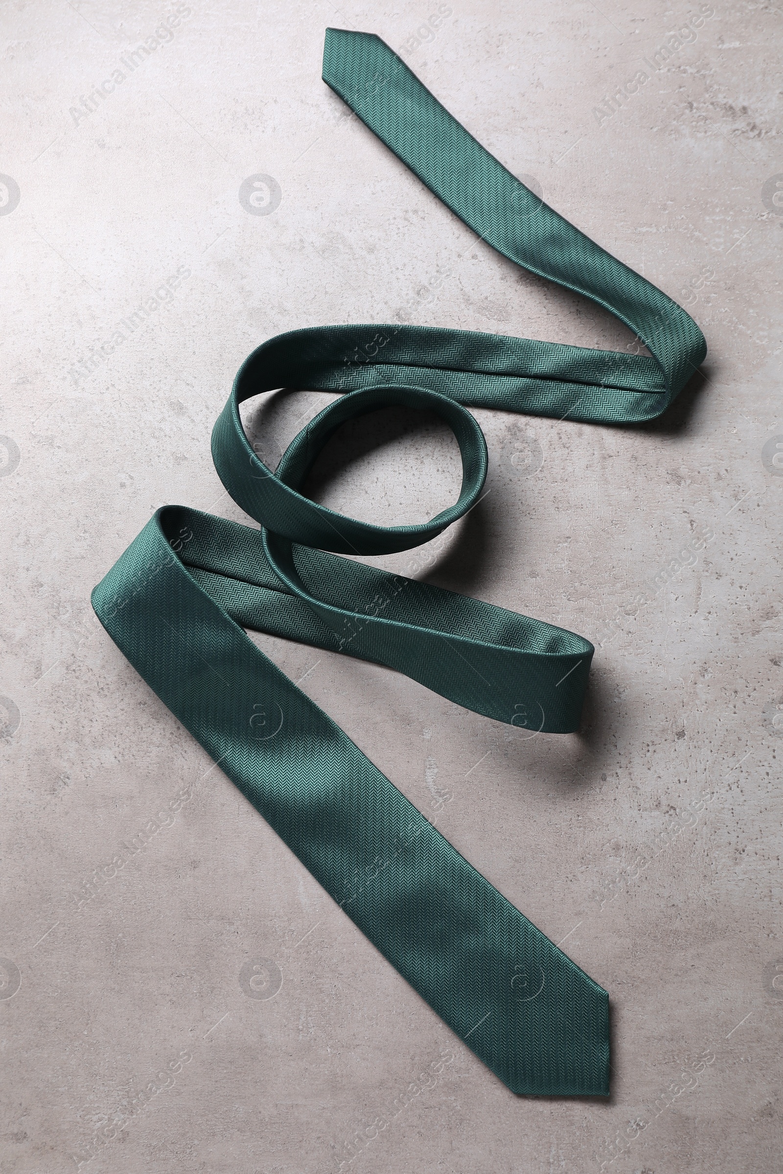 Photo of Stylish green necktie on grey table, top view