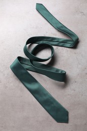 Stylish green necktie on grey table, top view