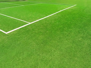 Photo of Tennis court with green grass and markings outdoors