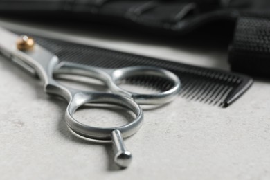 Photo of Hairdresser tools. Professional scissors, comb and leather organizer on white table, closeup