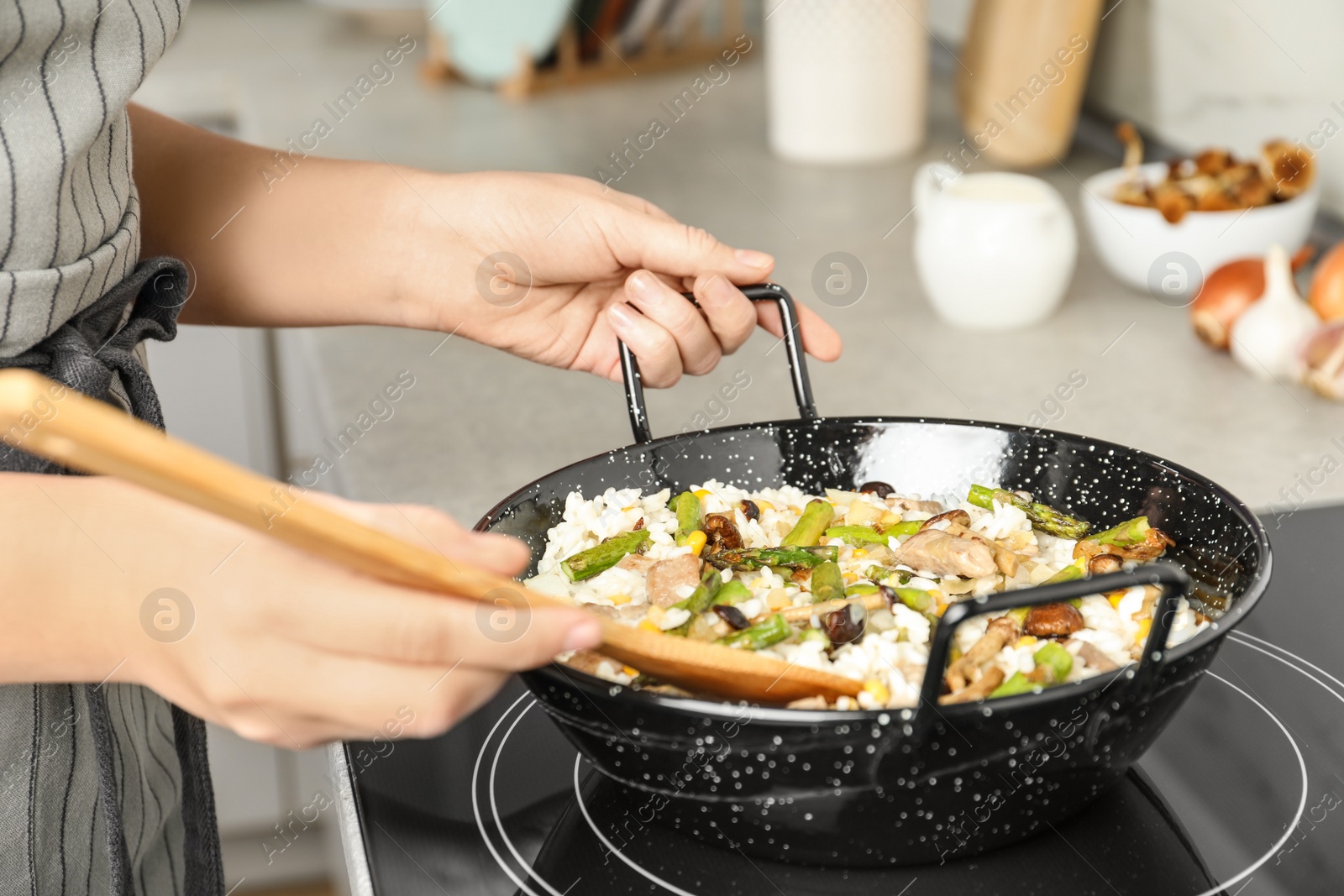 Photo of Woman cooking delicious risotto, closeup. Tasty recipe