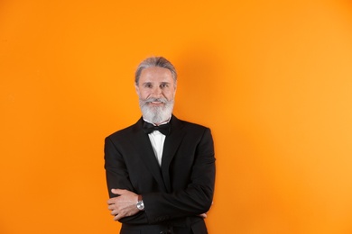 Photo of Handsome bearded mature man in suit on color background