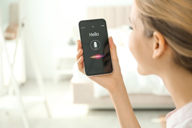 Photo of Young woman using voice search on smartphone indoors, closeup. Space for text