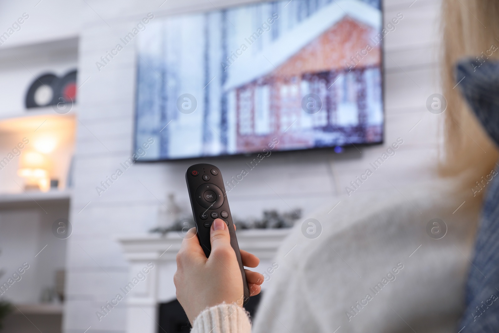 Photo of Woman with remote control watching TV at home, closeup