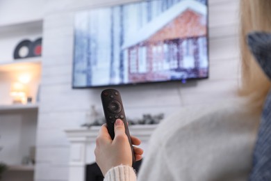 Photo of Woman with remote control watching TV at home, closeup