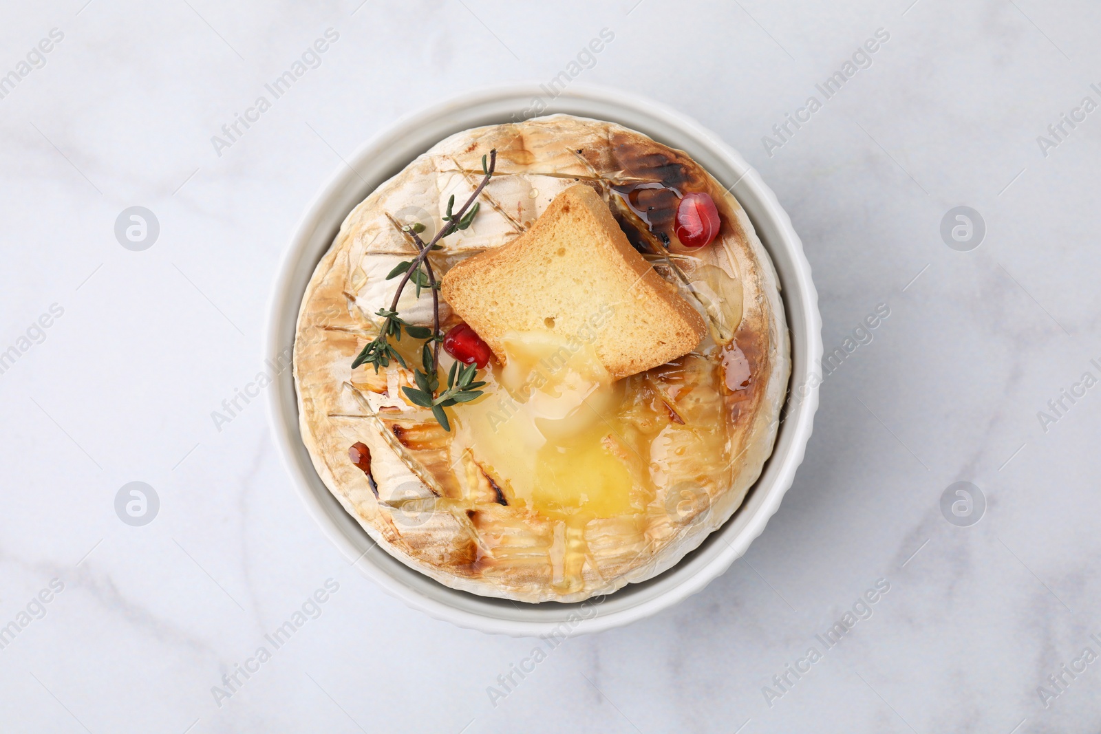 Photo of Tasty baked camembert with crouton and thyme on white marble table, top view