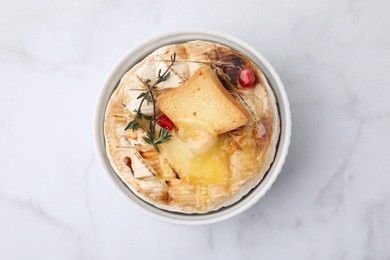 Tasty baked camembert with crouton and thyme on white marble table, top view