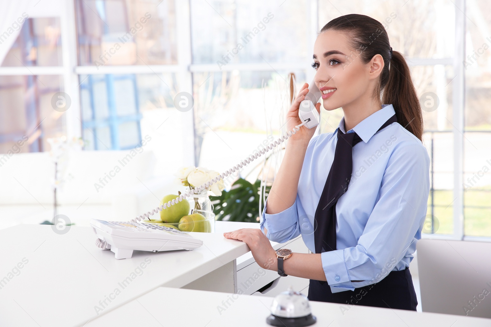 Photo of Female receptionist talking on phone at workplace in hotel