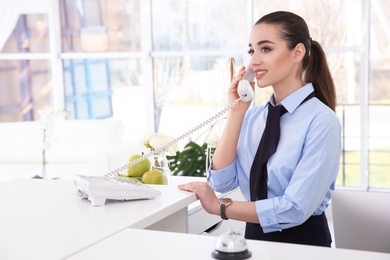 Photo of Female receptionist talking on phone at workplace in hotel