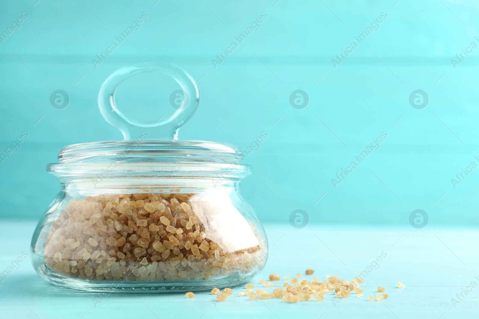 Photo of Glass bowl with brown sugar on light blue wooden table. Space for text