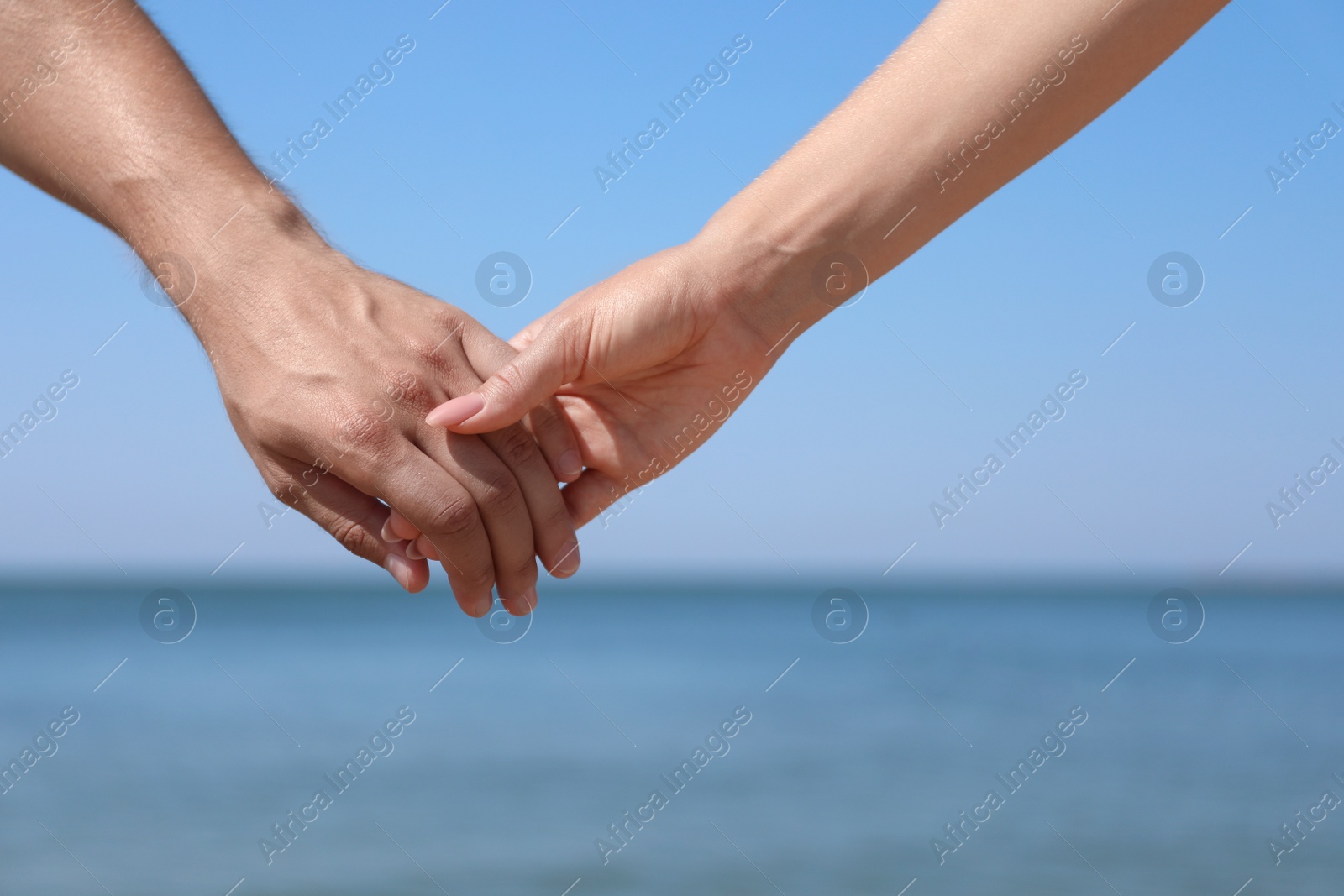 Photo of Happy couple holding hands at beach on sunny day, closeup