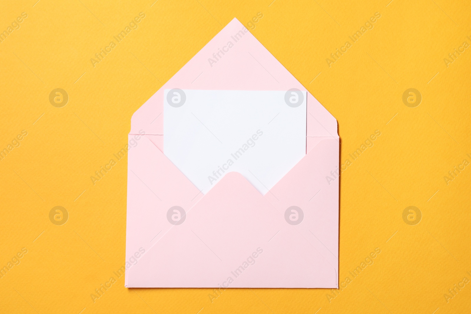 Photo of Blank sheet of paper in open letter envelope on orange background, top view