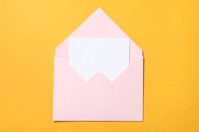Photo of Blank sheet of paper in open letter envelope on orange background, top view