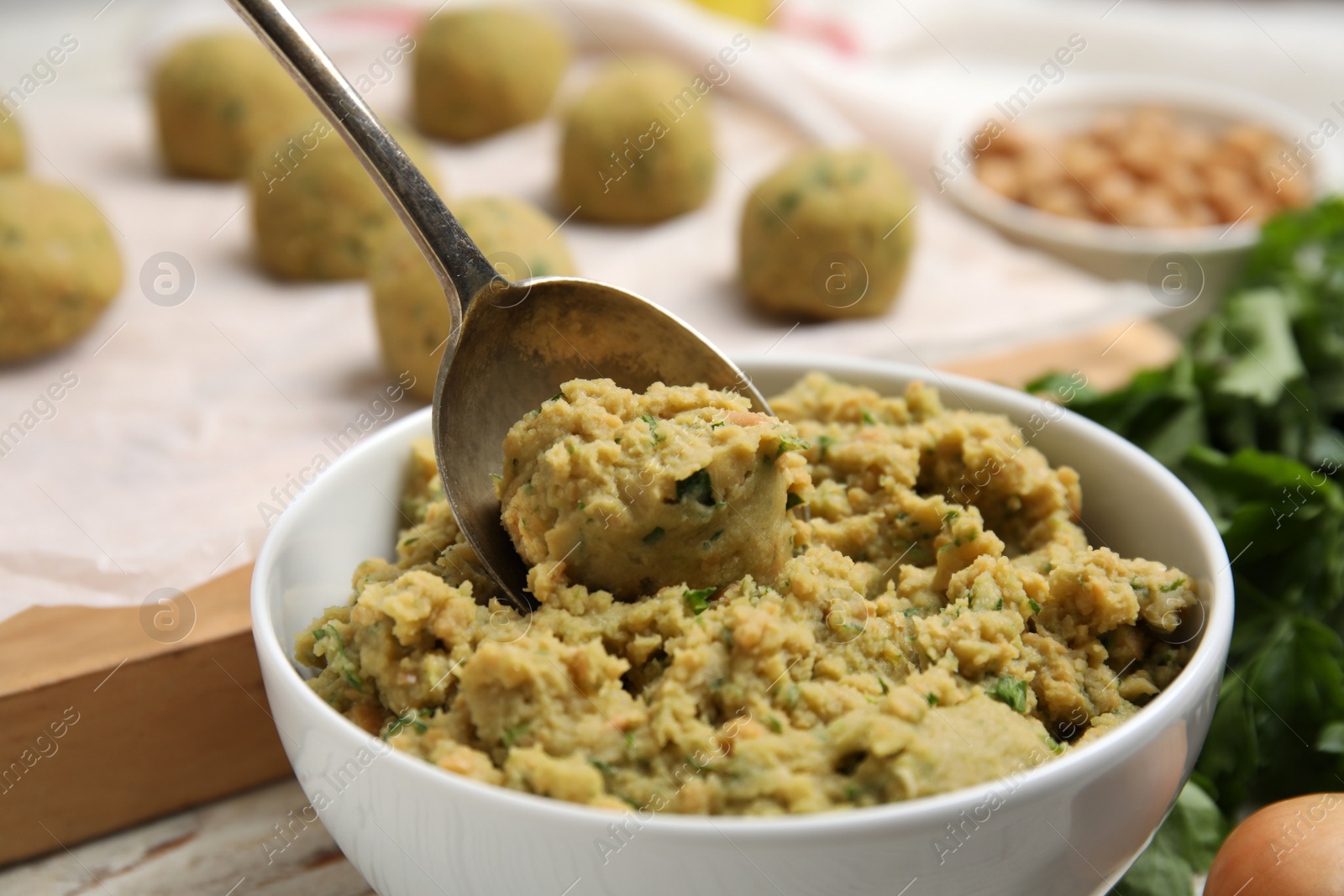 Photo of Bowl of chickpea puree with spoon on table, closeup. Falafel recipe