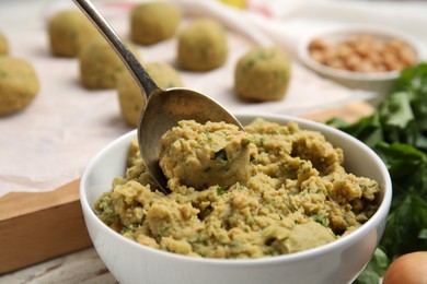 Bowl of chickpea puree with spoon on table, closeup. Falafel recipe