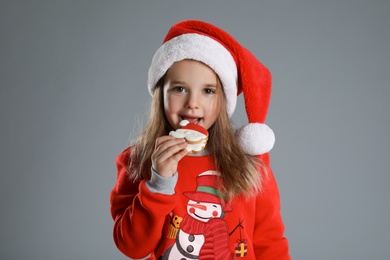 Photo of Cute little girl with Christmas gingerbread cookie on grey background