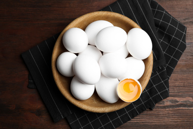 Photo of Many fresh raw chicken eggs in bowl on wooden table, flat lay