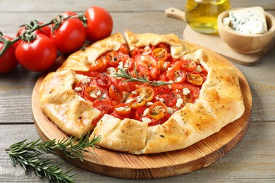 Photo of Tasty galette with tomato, rosemary and cheese (Caprese galette) on wooden table, closeup