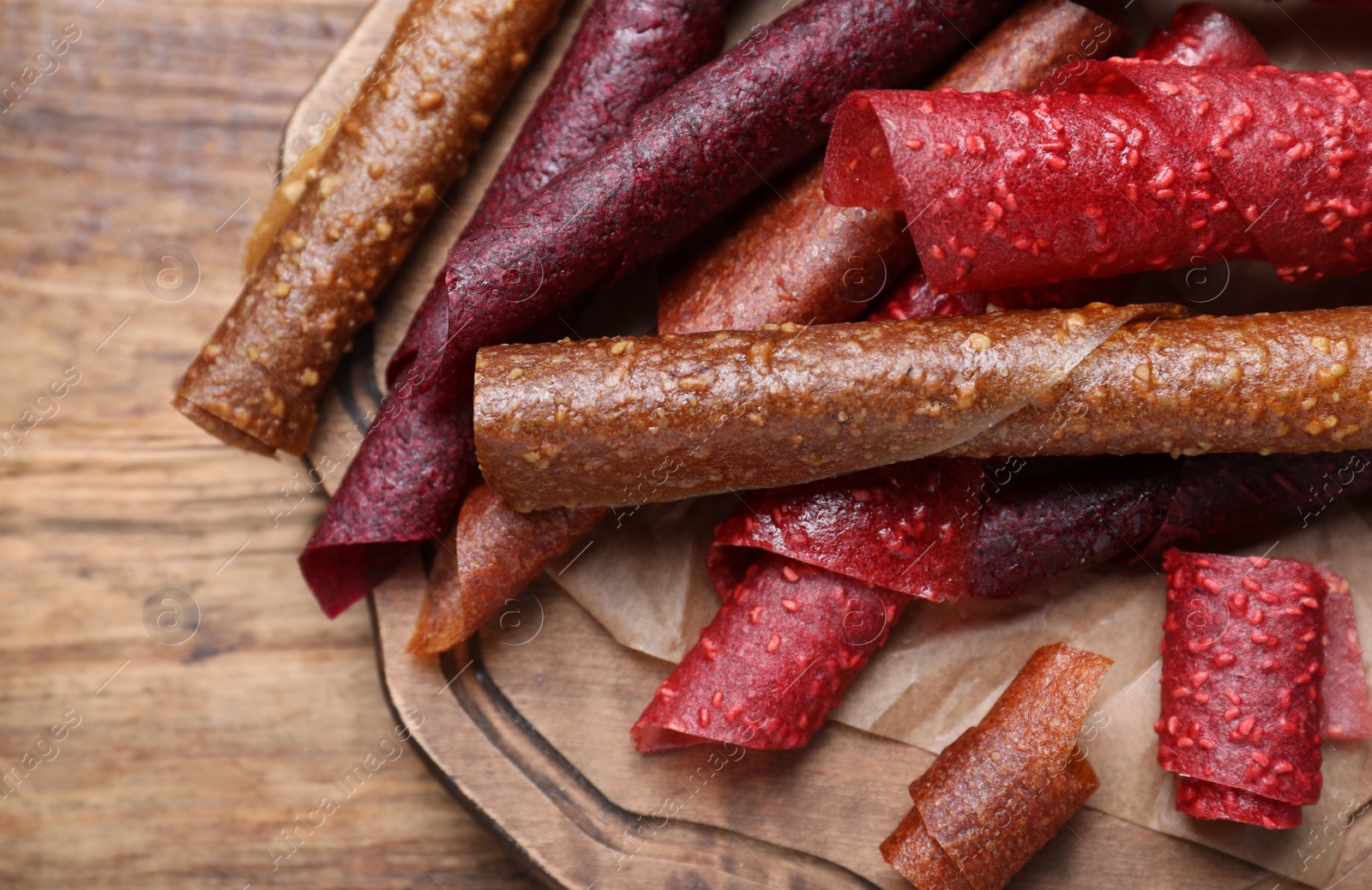 Photo of Delicious fruit leather rolls on wooden table, closeup