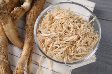 Photo of Grated horseradish and roots on grey wooden table, above view