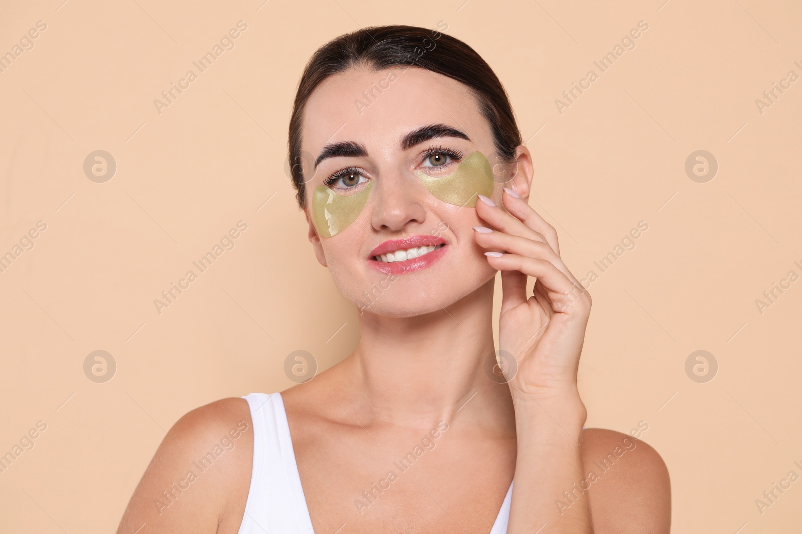 Photo of Beautiful woman with under eye patches on beige background