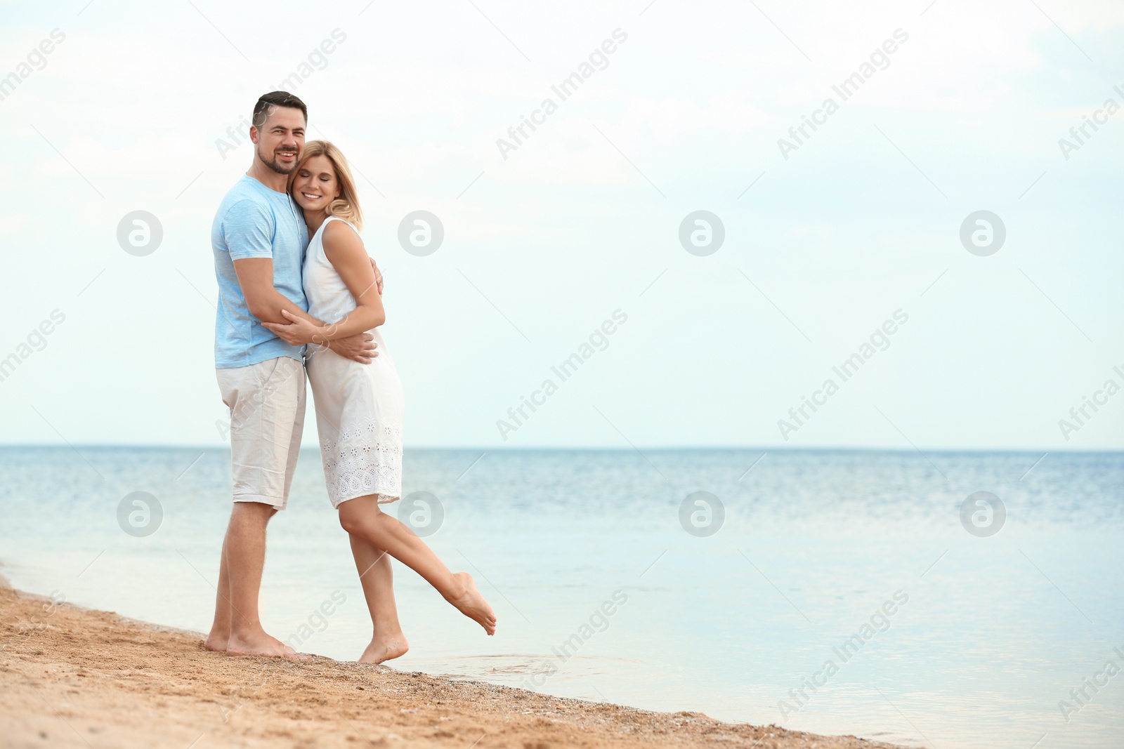 Photo of Happy romantic couple spending time together on beach, space for text