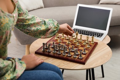 Woman playing chess with partner through online video chat in living room, closeup