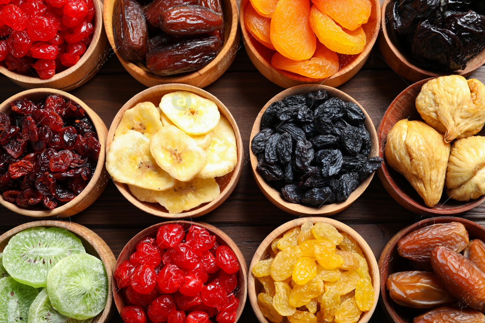 Photo of Bowls with different dried fruits on wooden background, flat lay. Healthy lifestyle