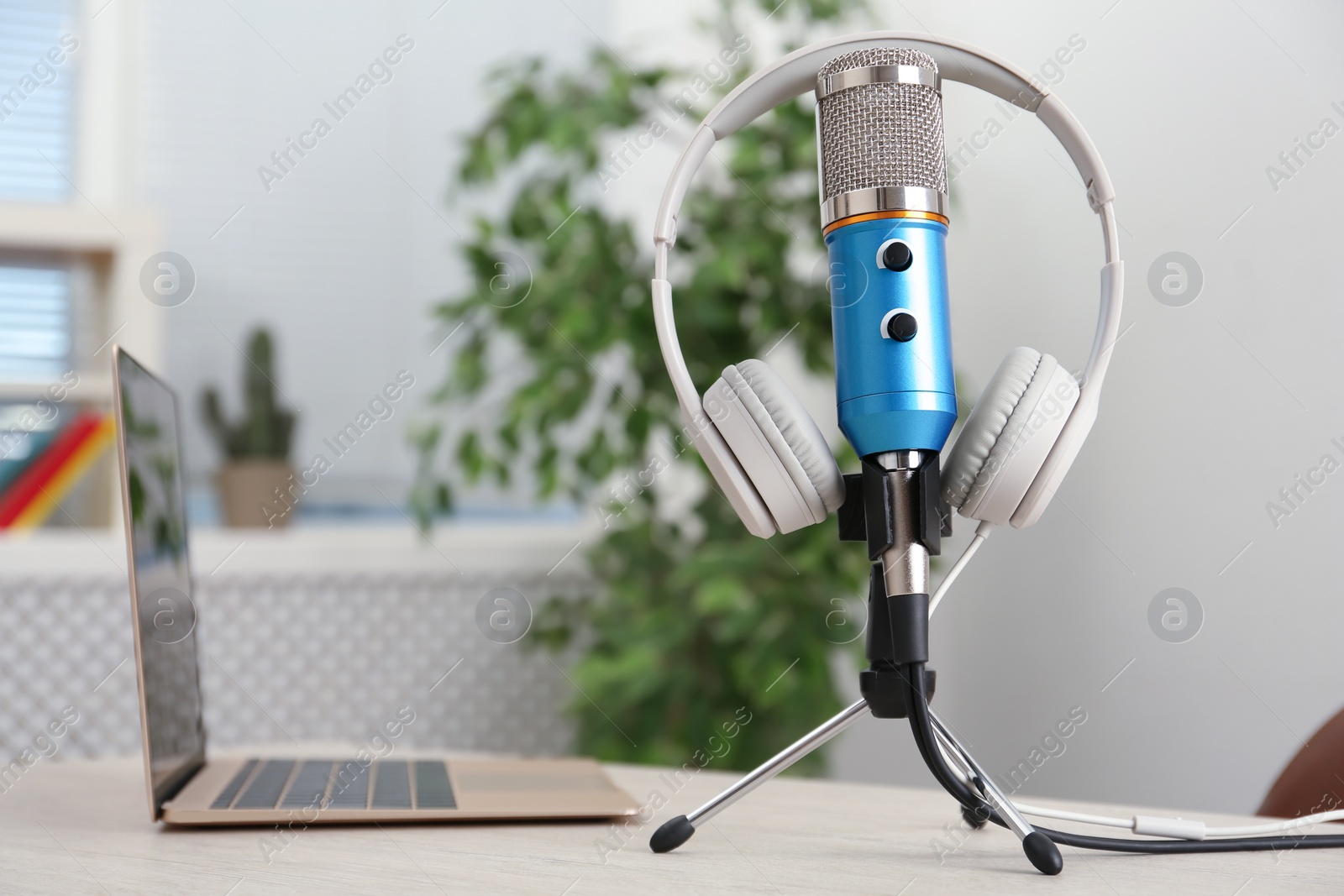 Photo of Microphone, modern headphones and laptop on table indoors