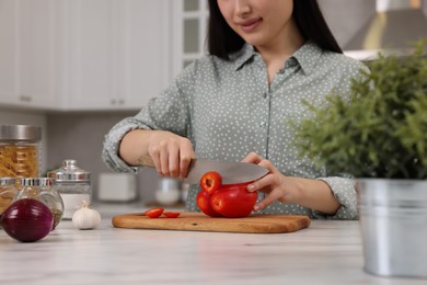 Cooking process. Woman cutting bell pepper at white countertop in kitchen, closeup