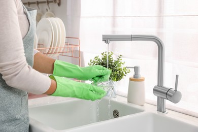 Woman washing glass at sink in kitchen, closeup