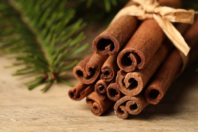 Photo of Bunch of cinnamon sticks and fir branches on wooden table, closeup. Space for text