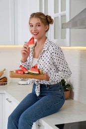 Photo of Beautiful teenage girl eating watermelon on countertop in kitchen