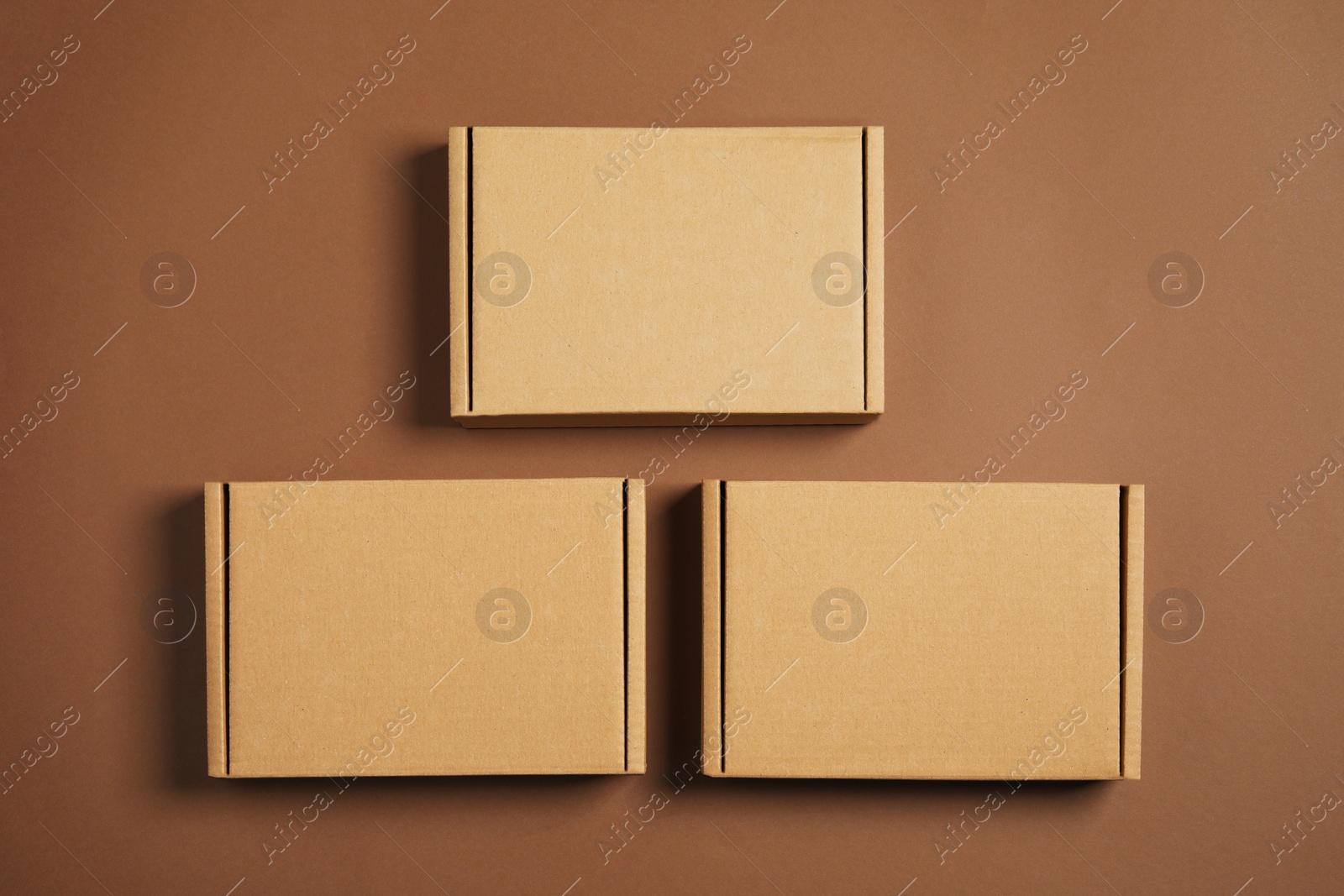 Photo of Many closed cardboard boxes on brown background, flat lay